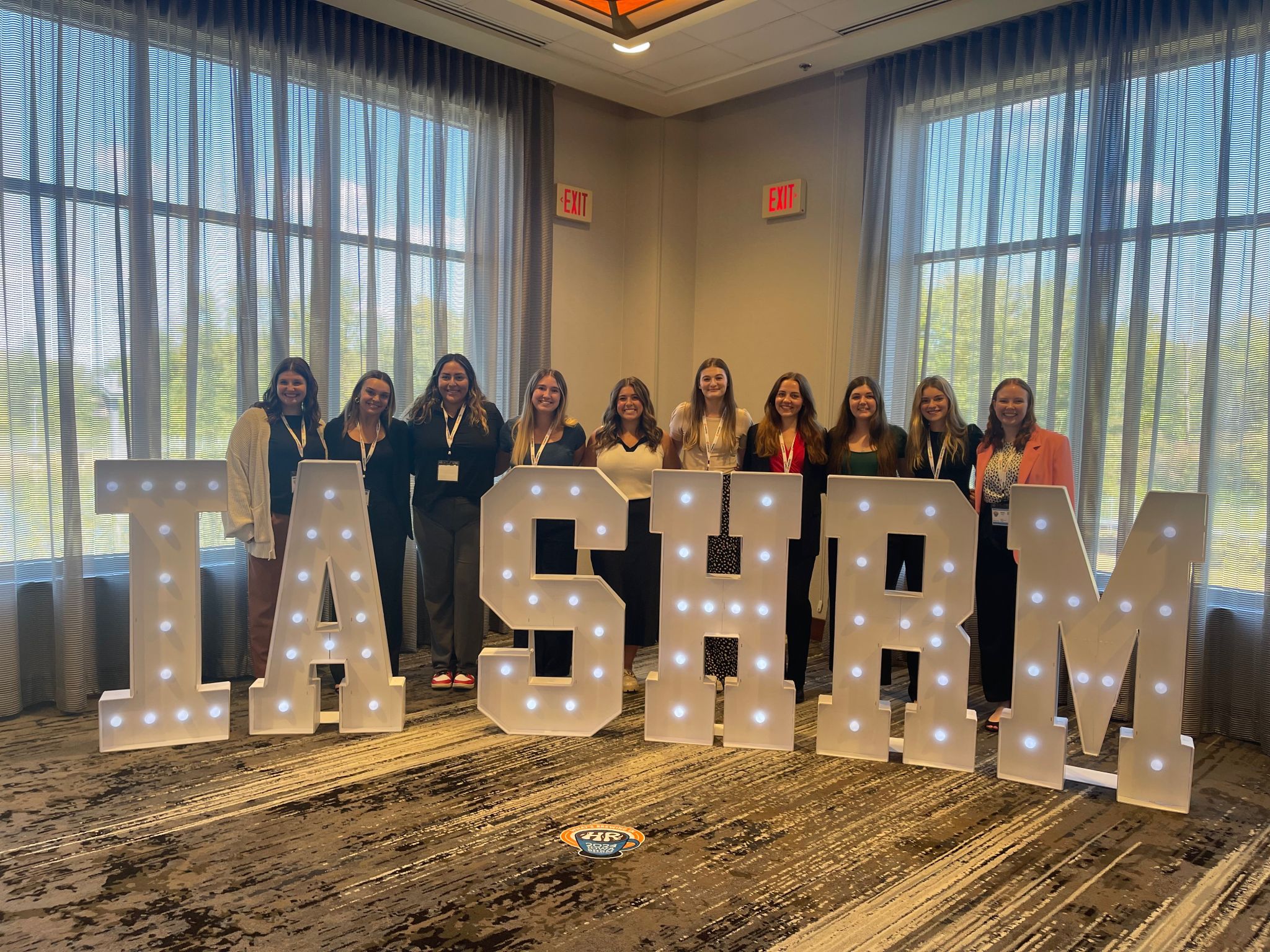 Conference member photo with a large sign that reads IA SHRM
